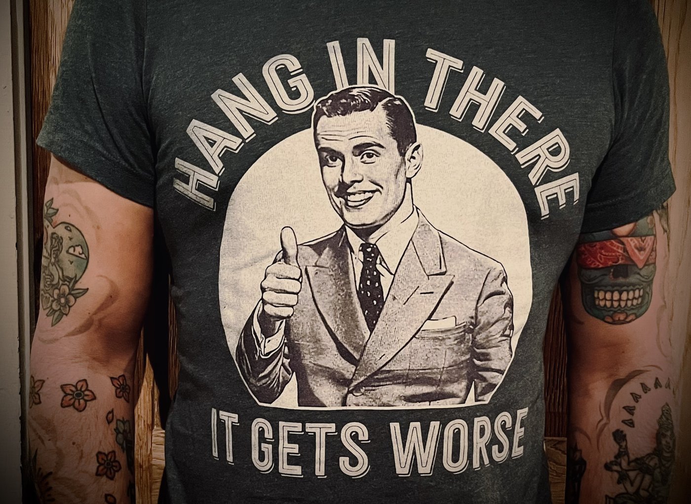 Close-up of Robin's t-shirt: a grinning vintage salesman giving a thumbs up, with the words Hang in there, it gets worse
