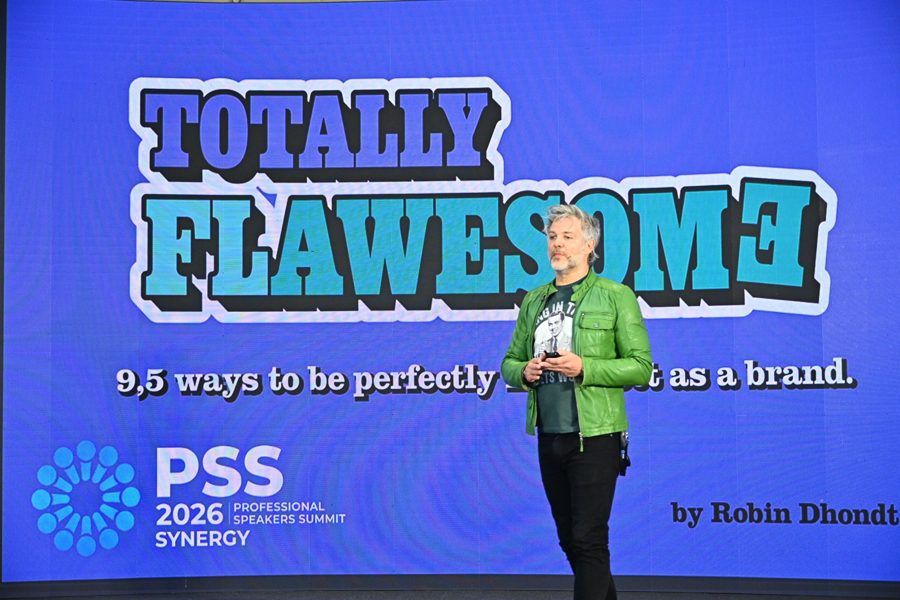 Robin on stage in his green leather jacket in front of the Totally Flawesome title slide