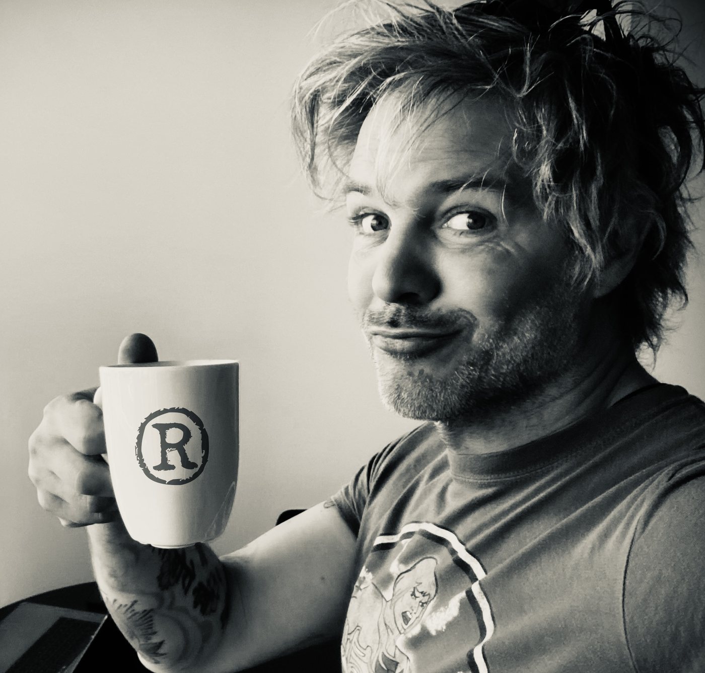 Black and white photo of Robin Dhondt raising a coffee mug with a registered trademark R on it