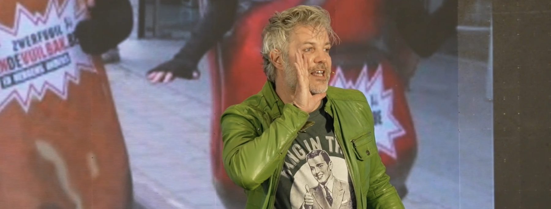 Robin Dhondt on stage in his green leather jacket, calling out to the audience